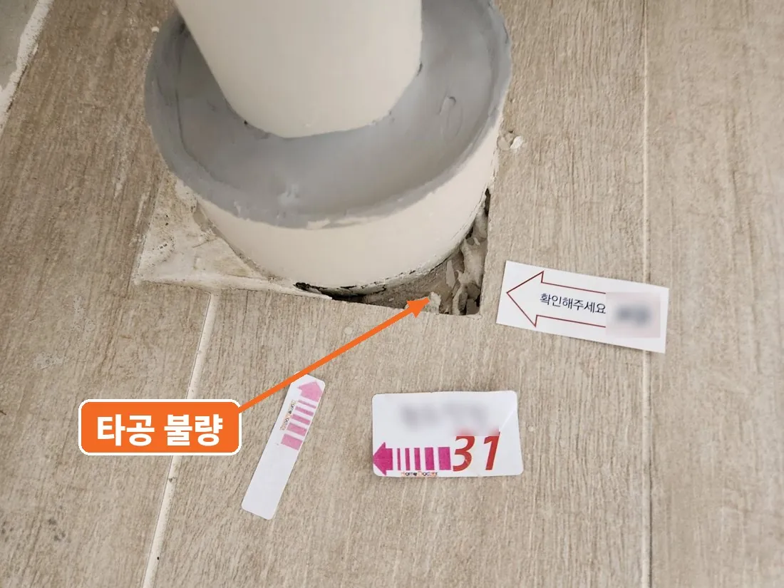배관 아래 바닥 타일을 크게 잘못 뚫어 생긴 틈, 타공 불량 표시와 31번 스티커