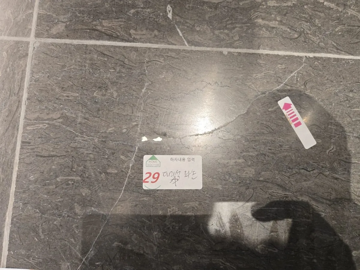대리석 바닥 타일이 갈라지고 깨진 자리를 흰 충전재로 메운 모습과 29번 대리석 파손 스티커